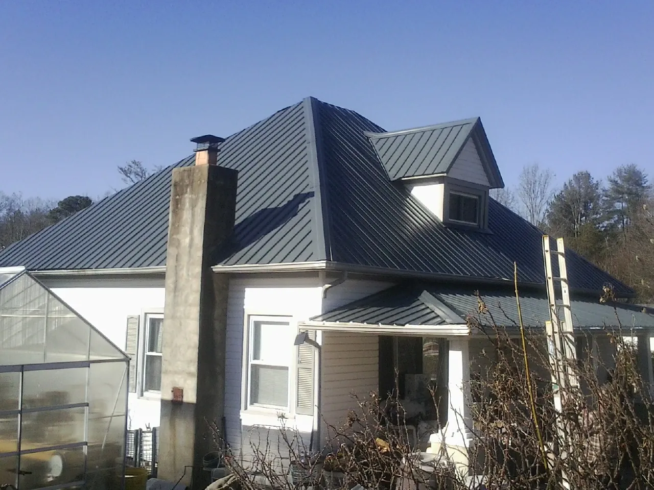Dark blue standing seam metal roof on a white farmhouse with dormer — Slate & Tile Roof Repair by Roofing Brothers in Mount Sterling