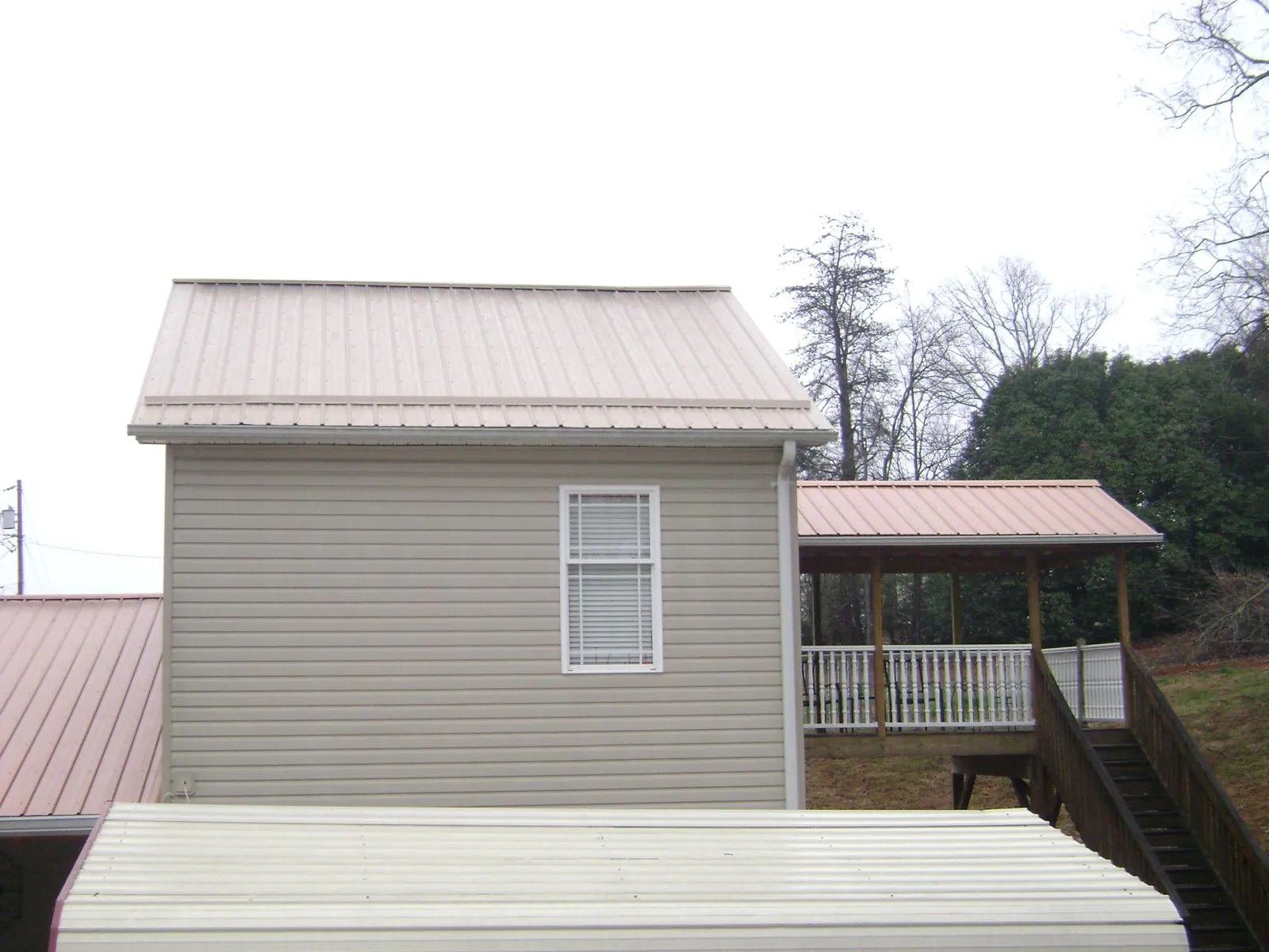 Tan metal roofs on a two story addition and attached porch, from a Roof Replacement job in Mount Sterling